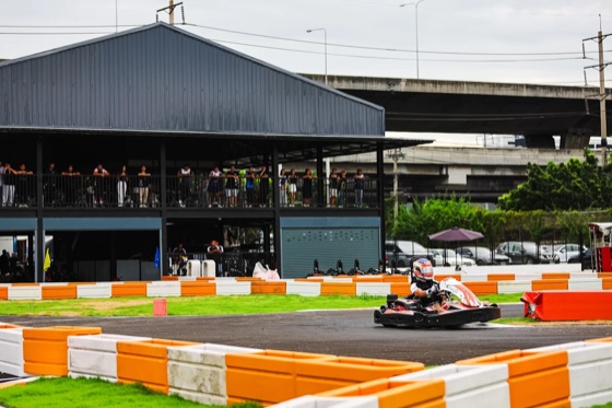 A kart on the track with spectators watching from the terrace